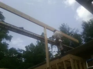Carpenter setting a ridge beam over a new addition frame — Ice Dam Removal by Roofing Brothers in Bunn