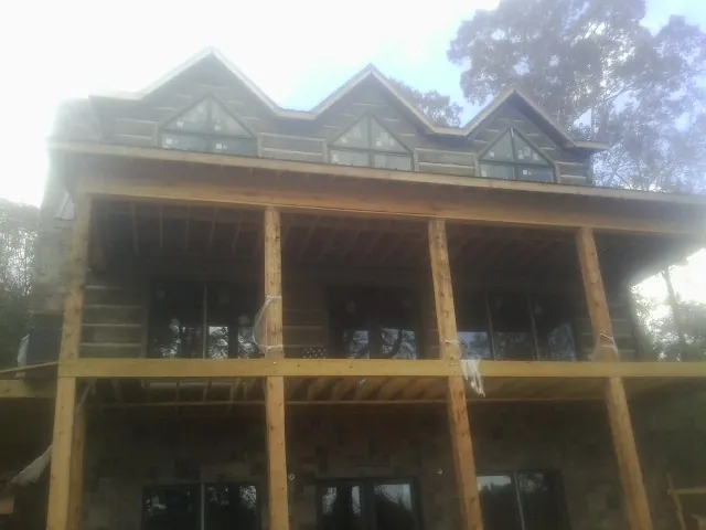 Dormers and porch framing on a large log home under construction — Roof Coating work by our crew in Bunn