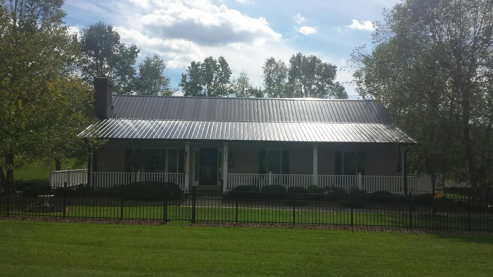Gray metal roof on a brick ranch with a full width front porch — Gutter Guard Installation work by our crew in Bunn