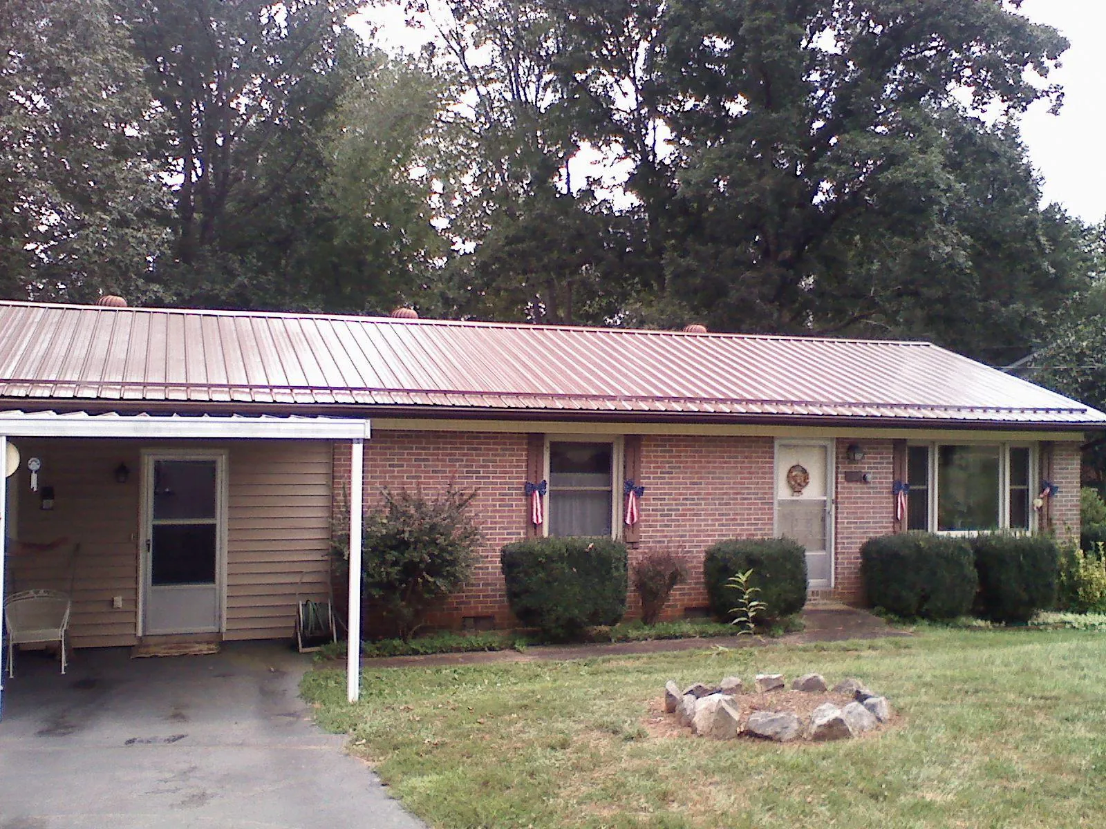 Bronze metal roof and carport on a brick ranch home — Roof Repair work by our crew in Bunn