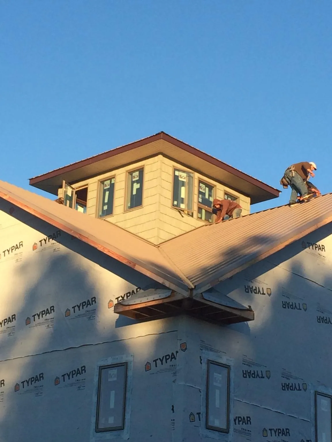 Roofers working around a rooftop cupola on a new metal roof at sunset — Roof Waterproofing in Bunn by Roofing Brothers